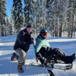 Don and Josh Routh pose and smile at Northstar. Josh is sitting in a bi-ski.